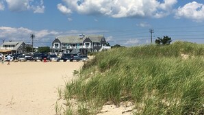 A beachfront hotel with multiple-story buildings, a parking lot, and a sandy beach area. - The Ocean View (Centerville)