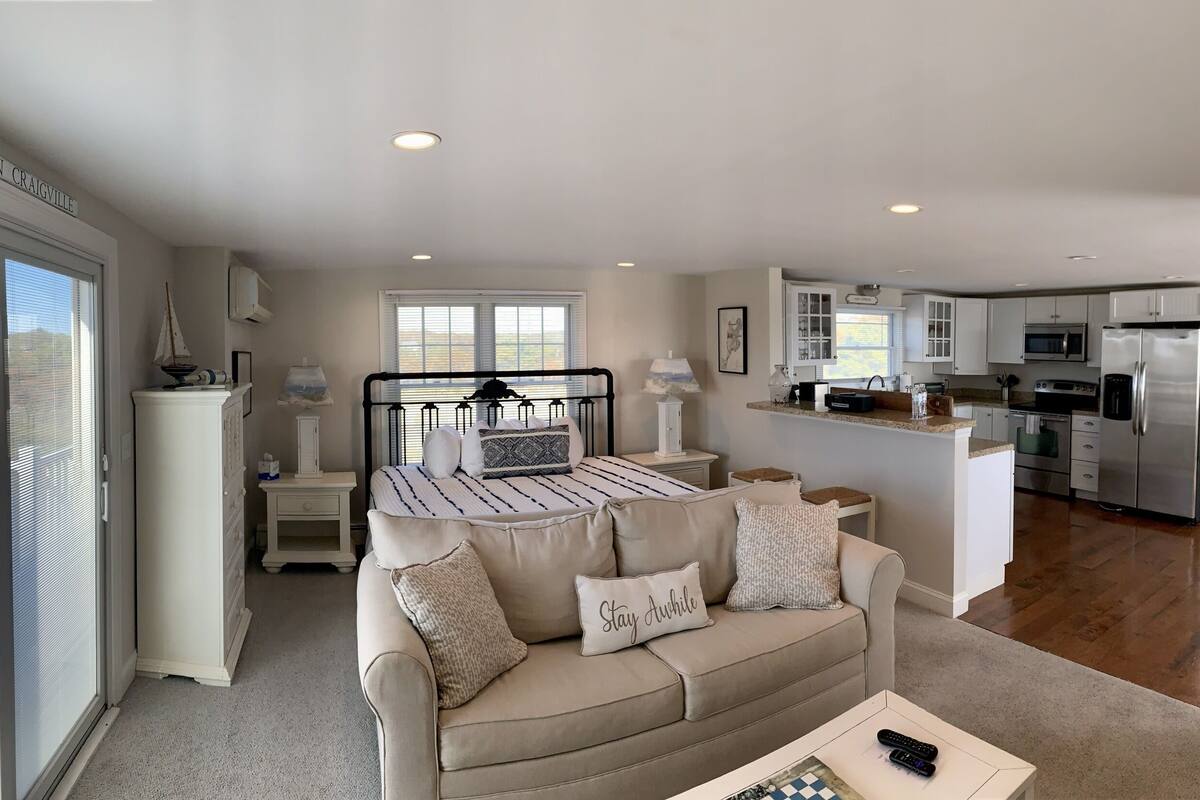 A bedroom with a bed, bedside tables, a nightstand, and a window. The room has a view of the outside.