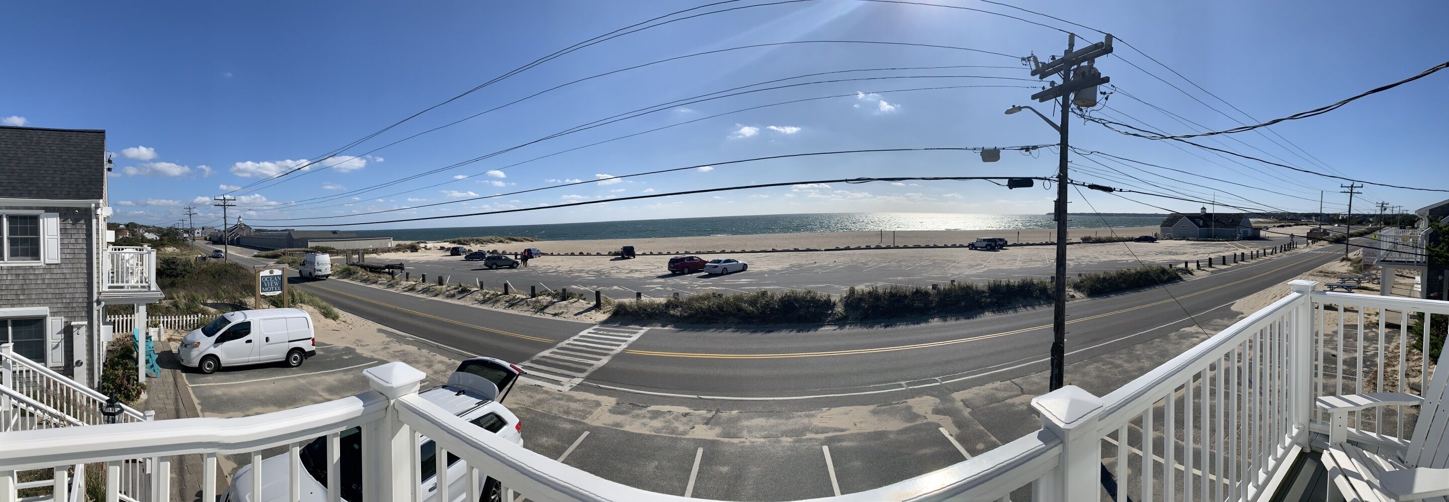 Una carretera costera con vista a la playa, un estacionamiento y un edificio con balcón.