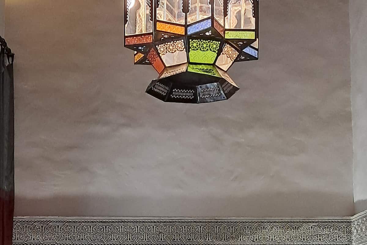 Une chambre à coucher avec un lit, des murs à motifs et un luminaire décoratif suspendu au plafond.