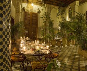 Un espace de restauration intérieur avec une table ronde, des chaises, des bougies et des plantes en pot.