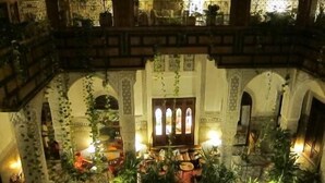 A multi-level atrium with ornate arches, potted plants, and a central seating area. - Riad Al Bartal (Fes)
