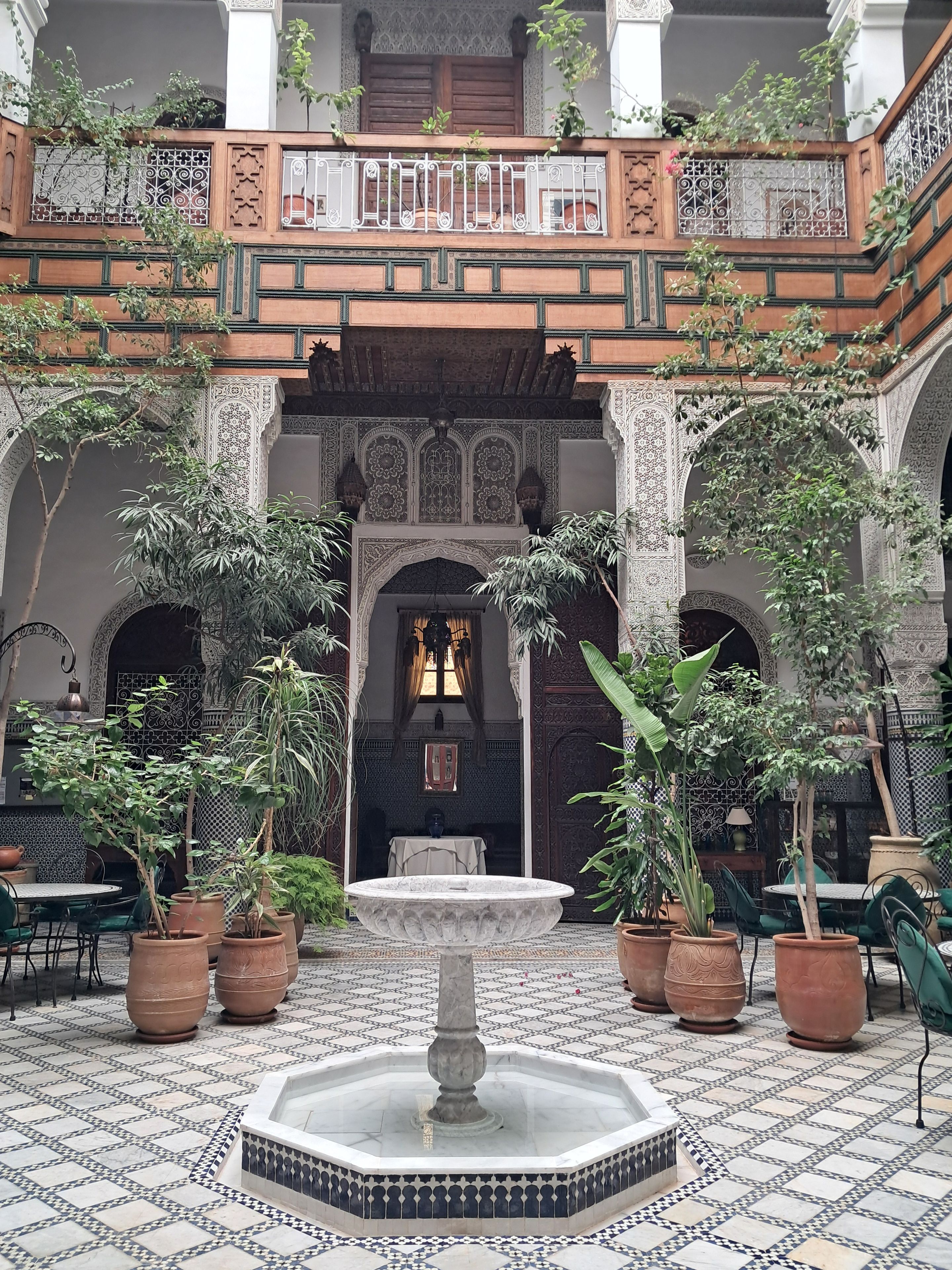 A courtyard with a central fountain, potted plants, and traditional architectural elements.
