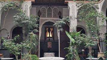 A courtyard with a central fountain, potted plants, and traditional architectural elements.