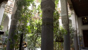 An interior courtyard with ornate columns, lush greenery, and traditional architectural details. - Riad Al Bartal (Fes)