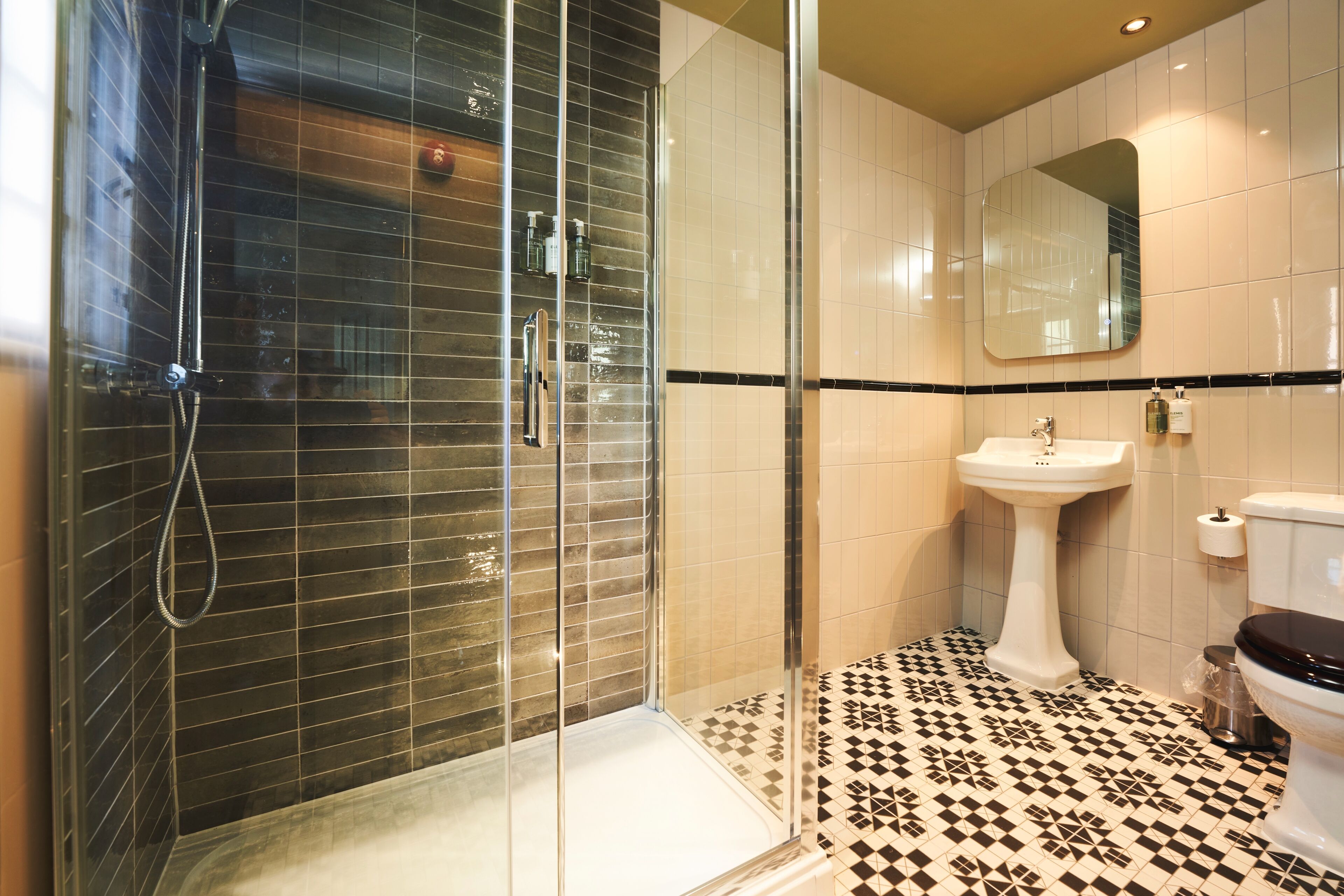 A modern bathroom with a glass-enclosed shower, a pedestal sink, and a toilet.