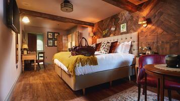 A bedroom with a wooden ceiling, a bed with a headboard, a desk, and a chair.