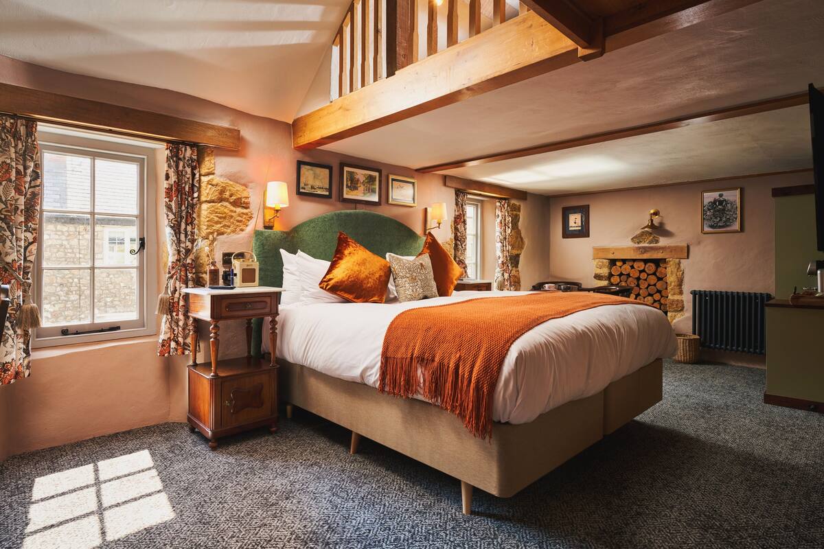 A bedroom with a large bed, wooden headboard, and a fireplace.