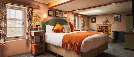 A bedroom with a large bed, wooden headboard, and a fireplace.