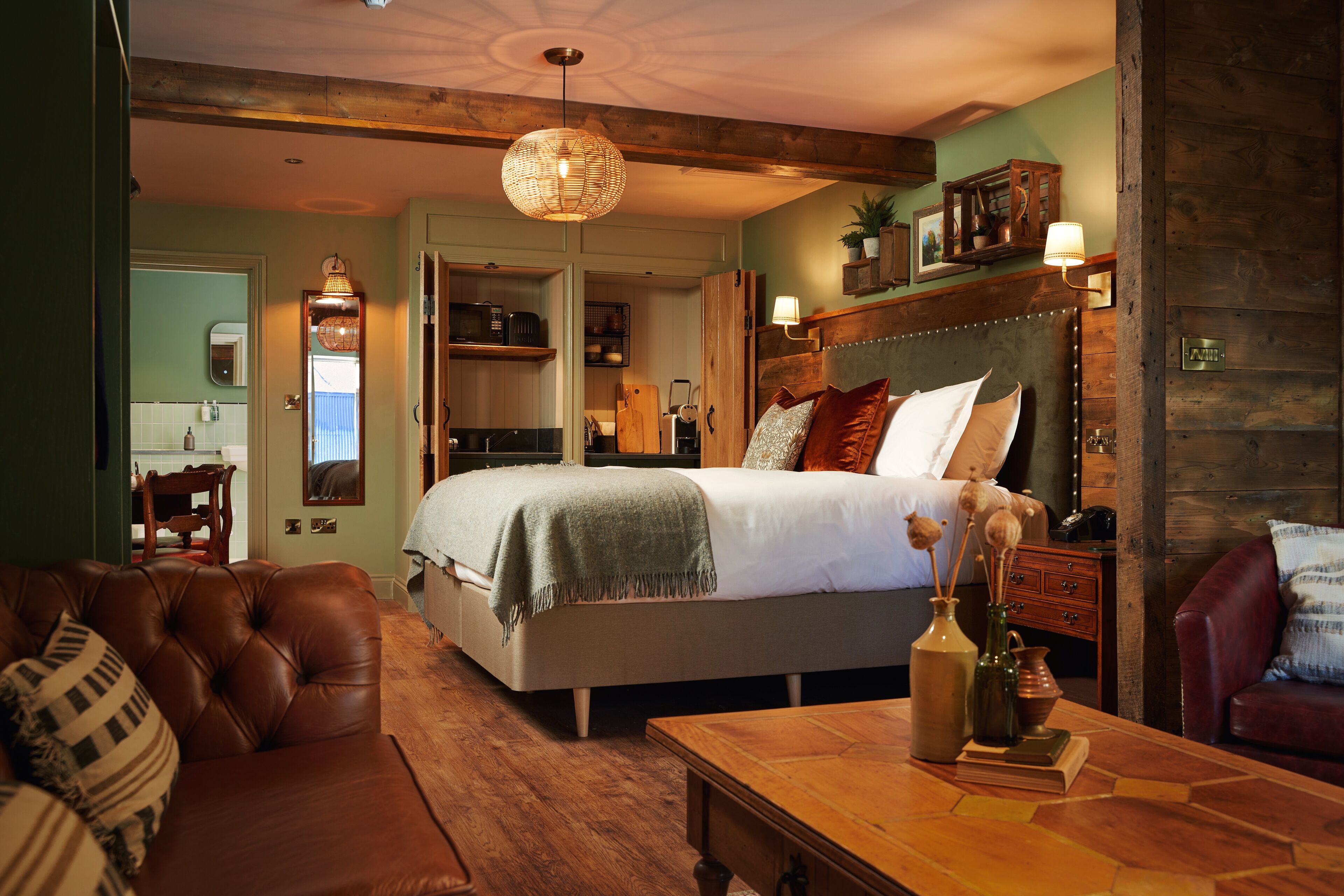 Un dormitorio acogedor con una cama grande, un sofá de cuero y una mesa de centro de madera.