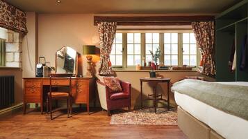 Une chambre à coucher avec une commode en bois, une chaise, un lit, une fenêtre avec des rideaux et un radiateur.