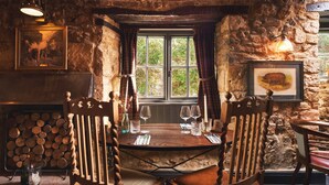 Un comedor rústico con pared de piedra, mesa y sillas de madera.