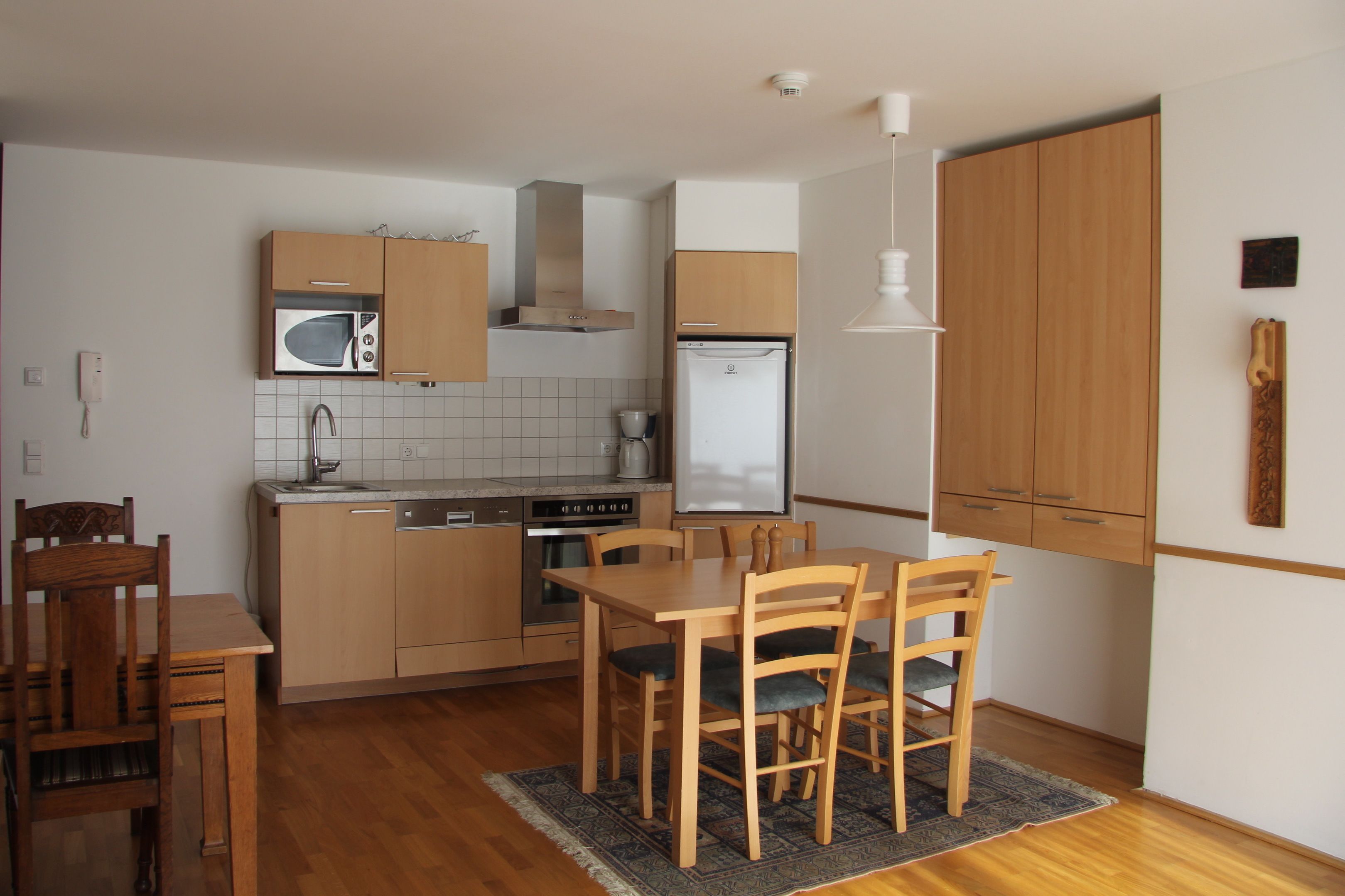 Una cocina compacta con armarios de madera, un microondas, una estufa y un refrigerador.