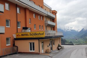 A hotel with a yellow sign, balconies, and a view of mountains. - Apartmenthotel Schillerhof (Bad Gastein)