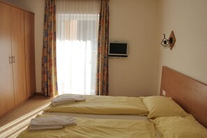 A bedroom with two beds, a TV, and a wardrobe. - Apartmenthotel Schillerhof (Bad Gastein)