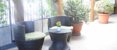 Un espace extérieur aménagé, abrité et doté de meubles en osier et de plantes en pot.