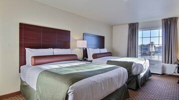 A hotel room with two beds, a window with curtains, and a view of the outside.