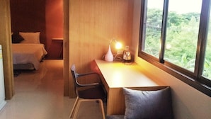 Une pièce confortable avec un lit, un bureau et une chaise, et une fenêtre donnant sur un paysage verdoyant.
