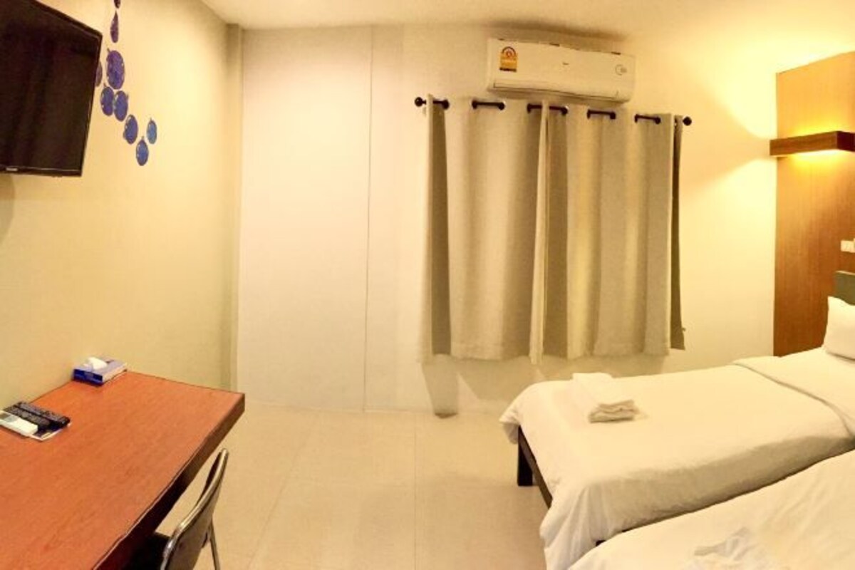 A hotel room with a bed, a desk, and a TV.