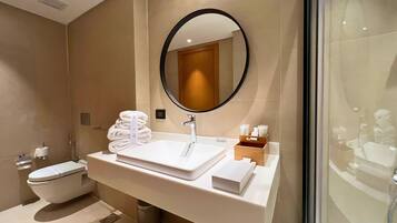 Un baño moderno con un lavabo blanco, un espejo redondo y un inodoro.