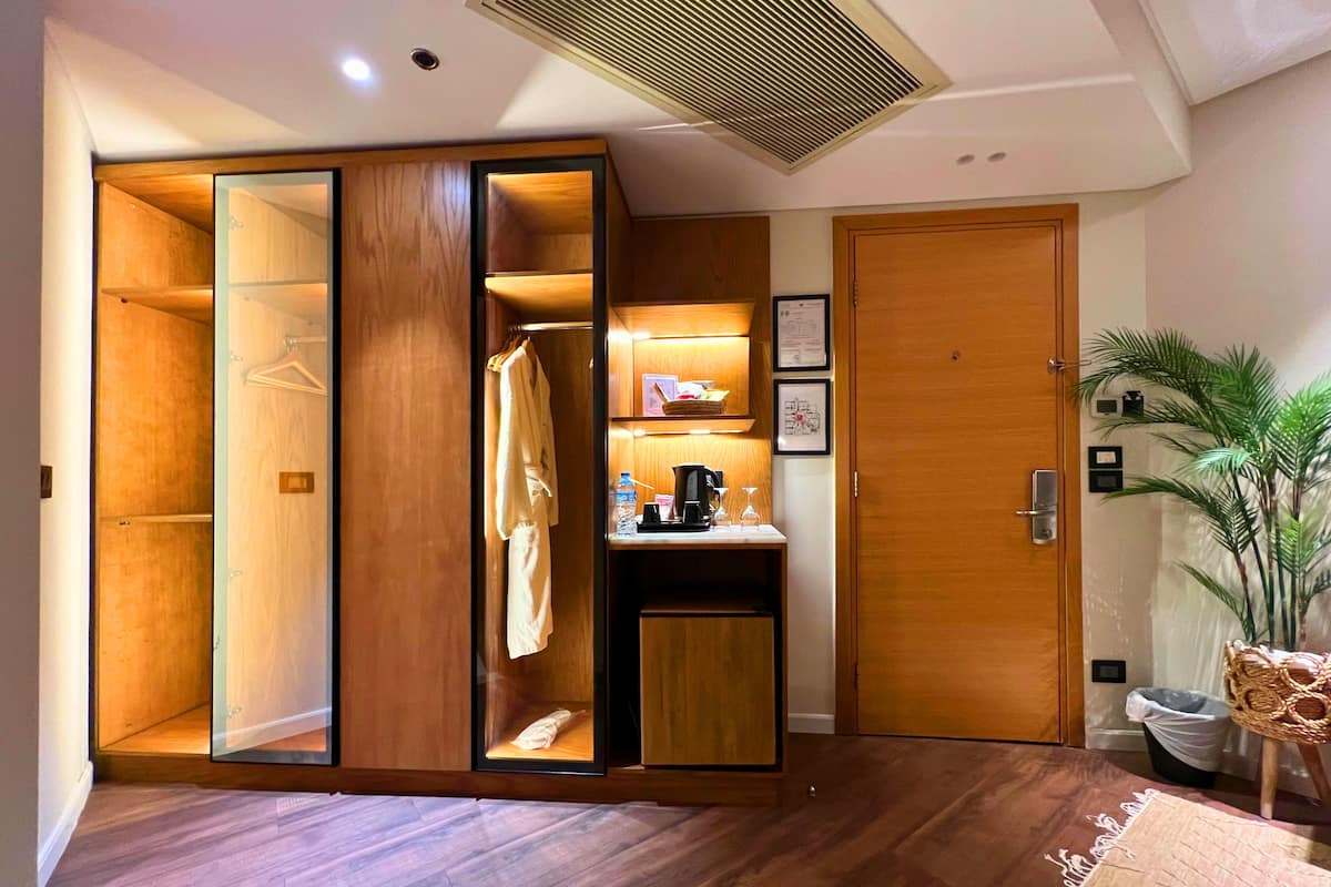 A walk-in closet with wooden shelving, a small desk with a coffee maker, and a potted plant.