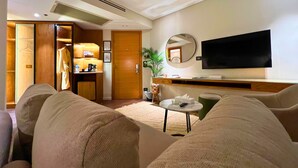 A hotel room with a living area featuring a sofa, a coffee table, a TV, and a wooden wardrobe. - New President Hotel Cairo (Cairo)