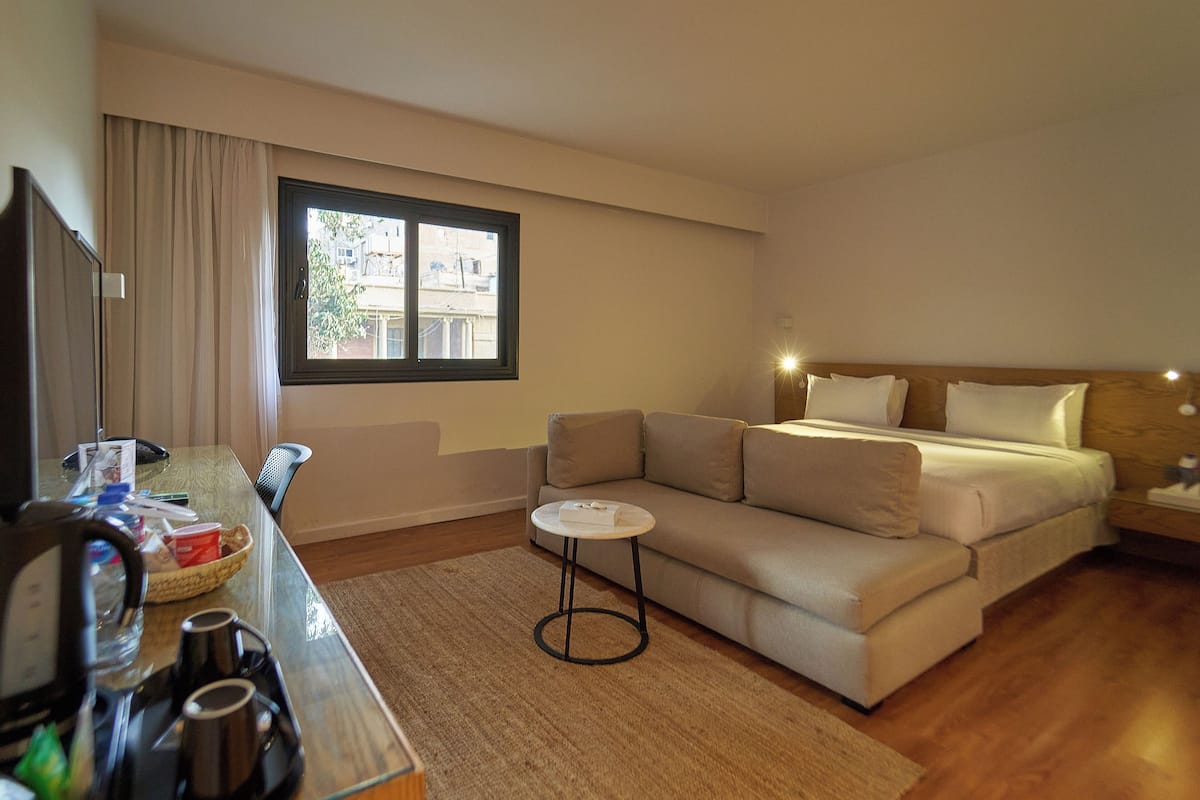 A hotel room with a bed, a sofa, a small table, and a TV.