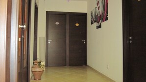 A hallway with two dark wooden doors, a tiled floor, and a potted plant. - B&B Anthea dell'Etna (Santa Venerina)