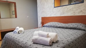 A neatly made bed with a patterned bedspread and two rolled towels. - B&B Anthea dell'Etna (Santa Venerina)
