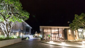 Un edificio bien iluminado con ventanas amplias y un área de acceso pavimentada.