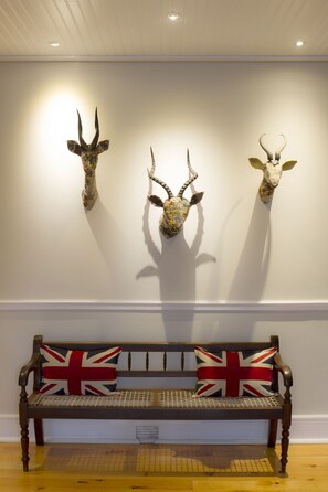 A bench with a Union Jack cushion, mounted on a wall with three mounted animal heads. - Royal St. Andrews Hotel, Conference Centre & Spa (Port Alfred)