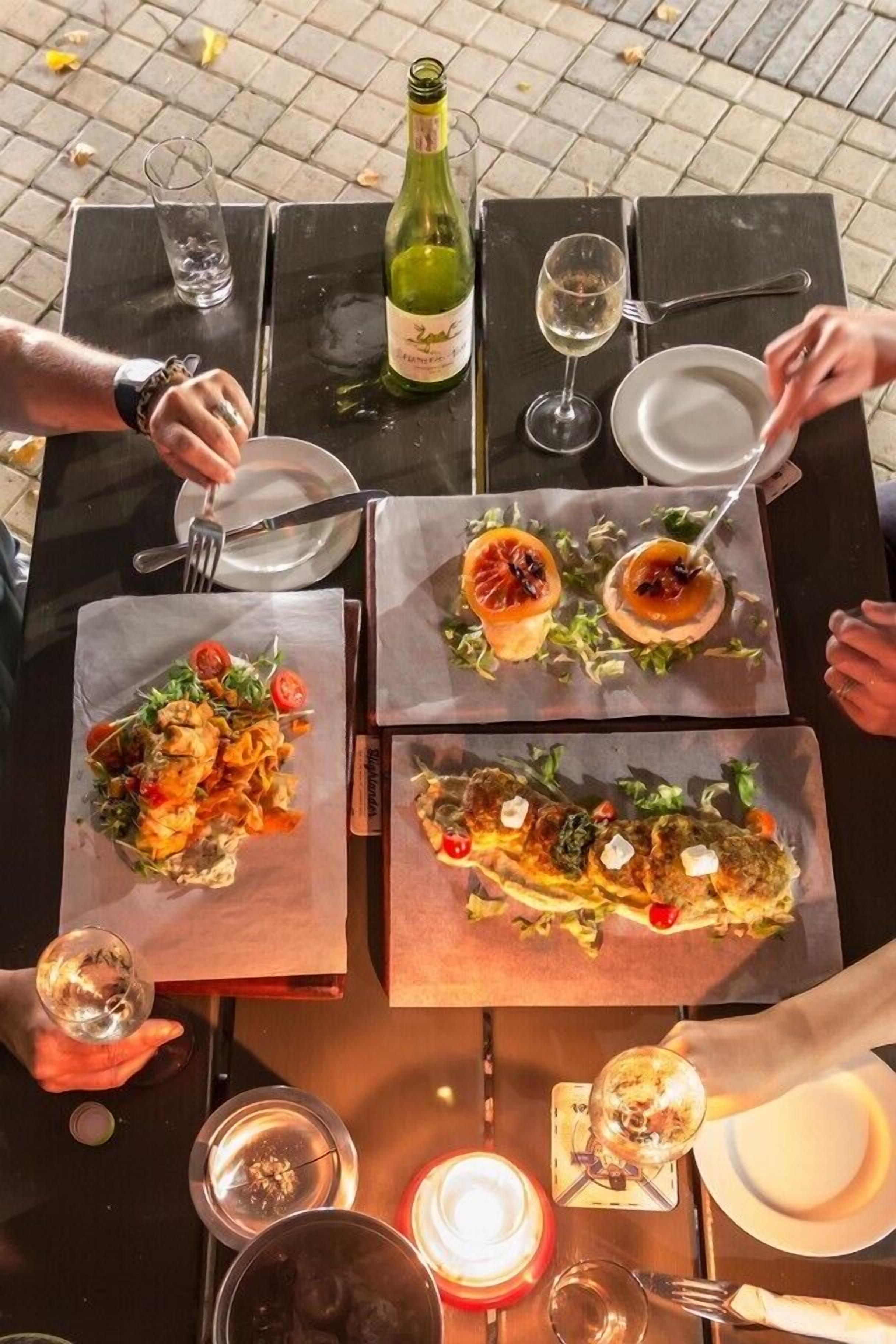 A table set for a meal with plates of food, a bottle of wine, and glasses.
