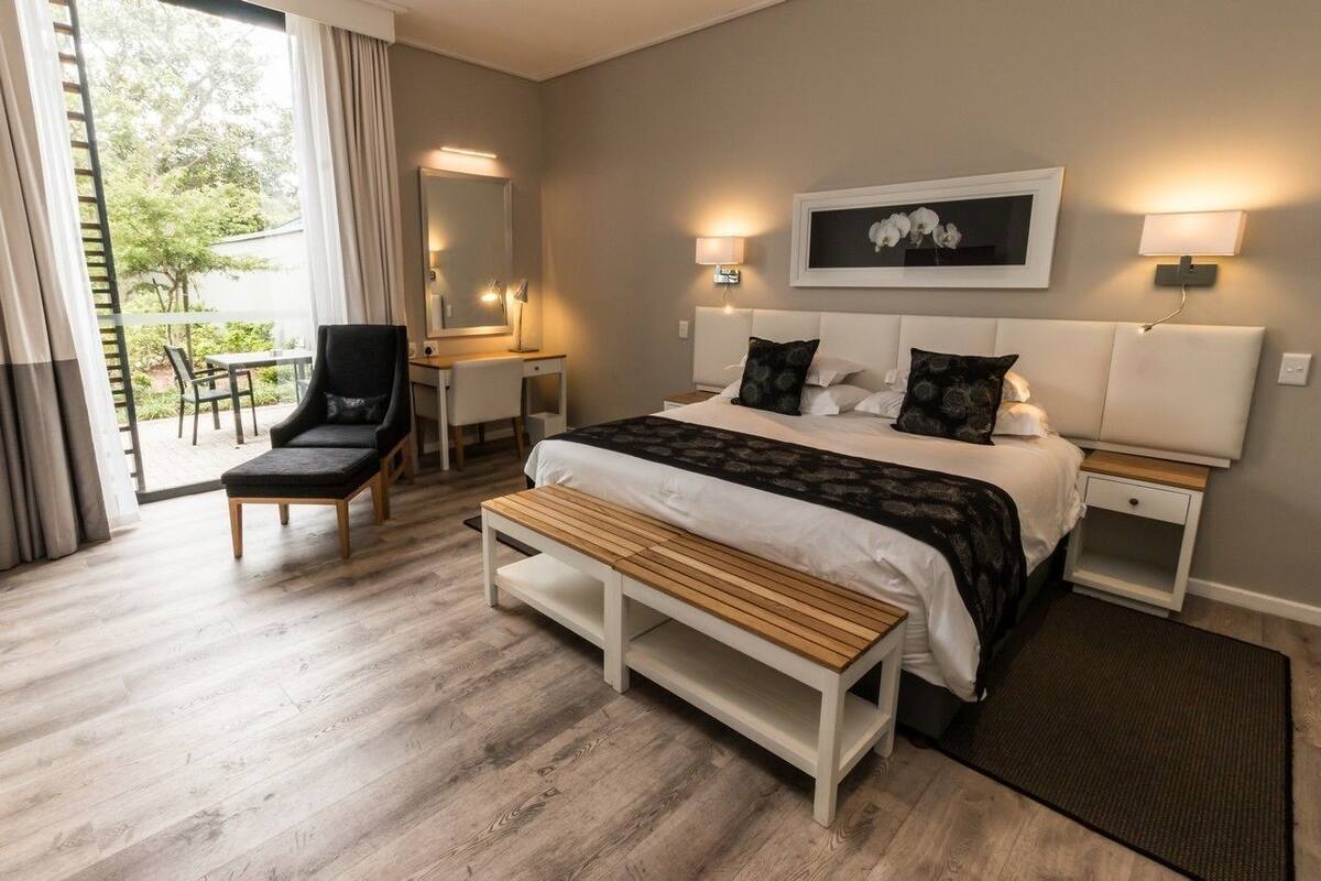 Un dormitorio con cama, mesitas de noche, una banca, un escritorio y una silla.