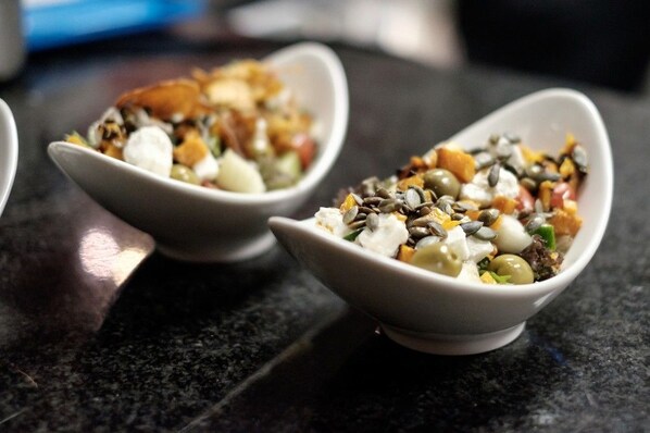 Two white bowls on a dark countertop containing a salad with various ingredients. - Royal St. Andrews Hotel, Conference Centre & Spa (Port Alfred)