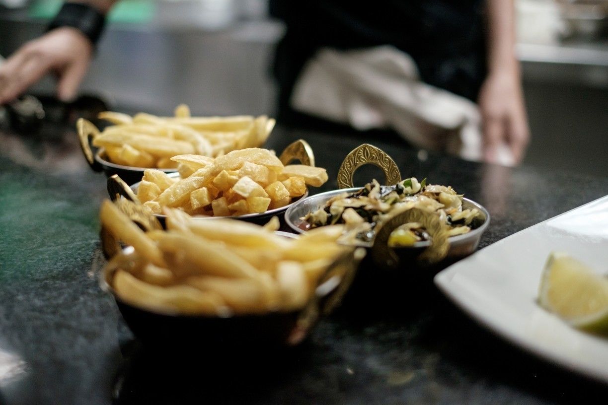Une table avec trois bols de frites et une assiette avec un quartier de citron vert.