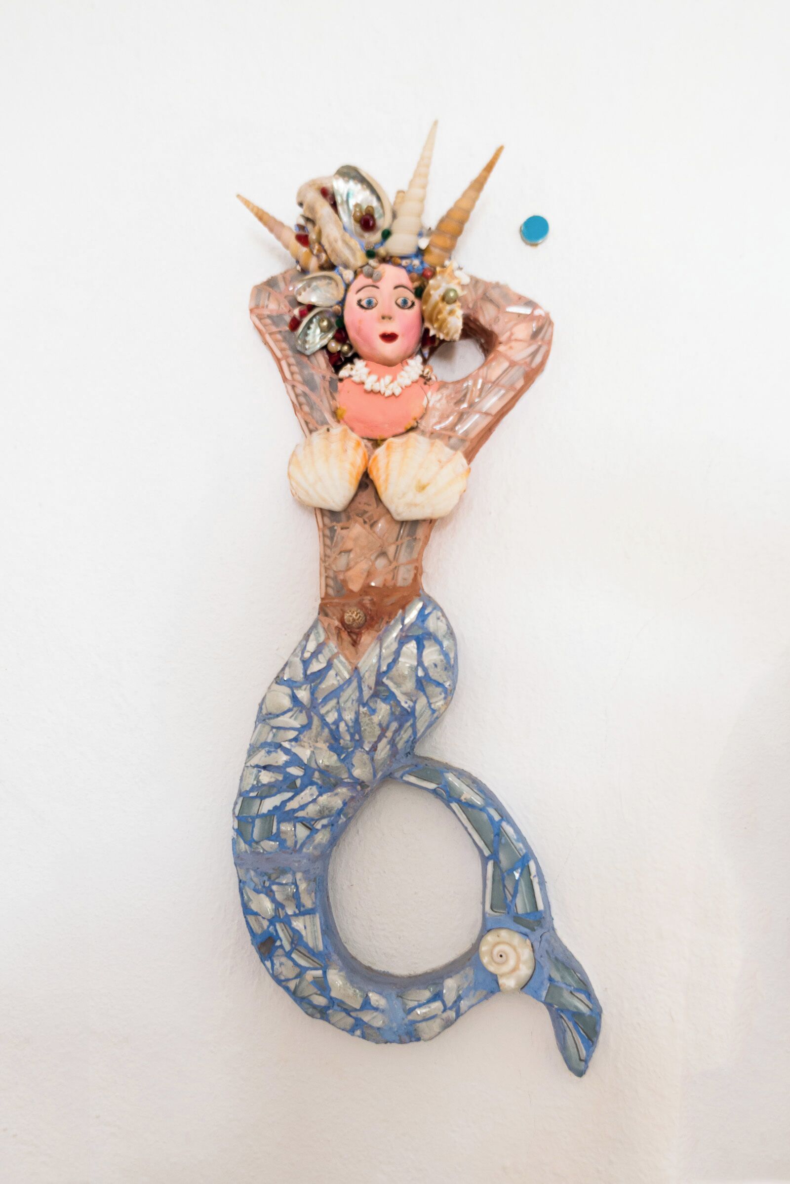 Una pieza decorativa con una cola de sirena, una figura y conchas marinas.