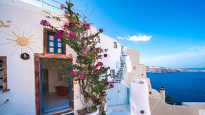 Un edificio blanco con una puerta azul y una escalera que lleva a un balcón con vistas al mar.