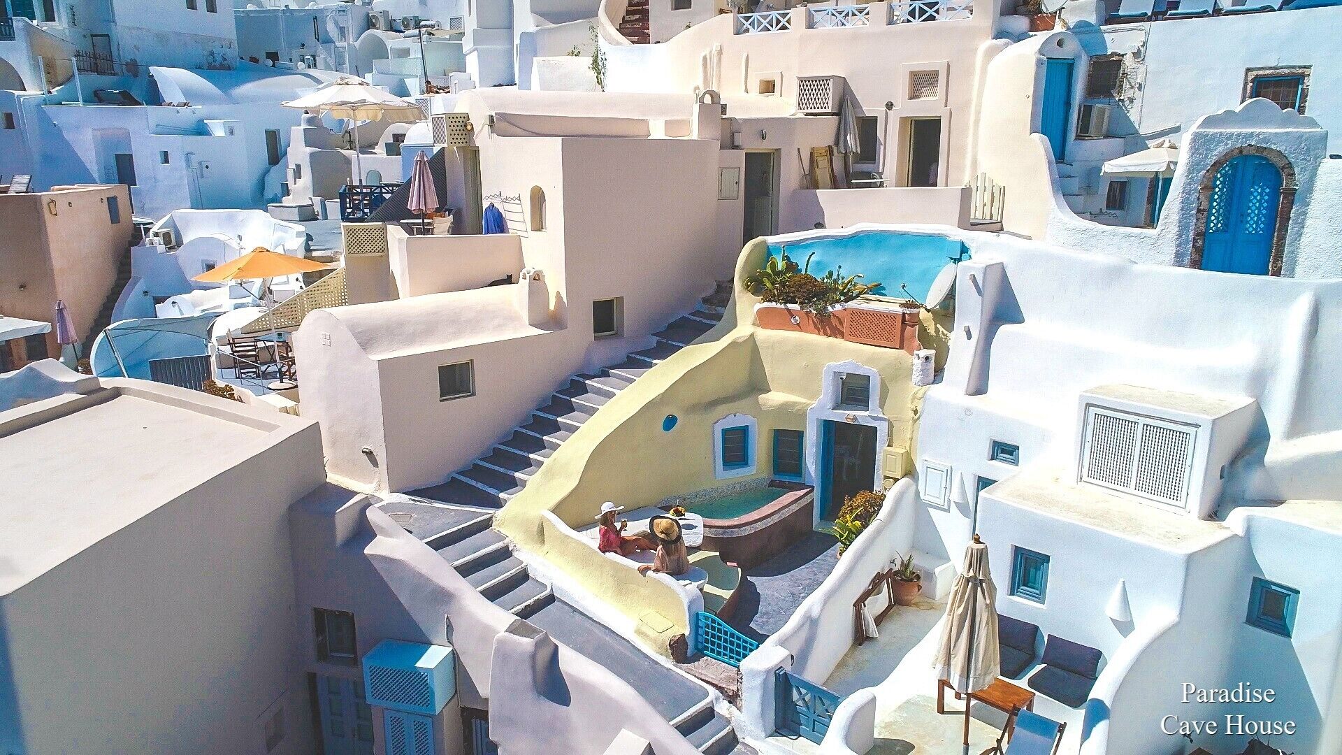 Un bâtiment aux murs blanchis à la chaux, agrémenté de touches de bleu, avec un escalier menant à une terrasse sur le toit et une piscine.