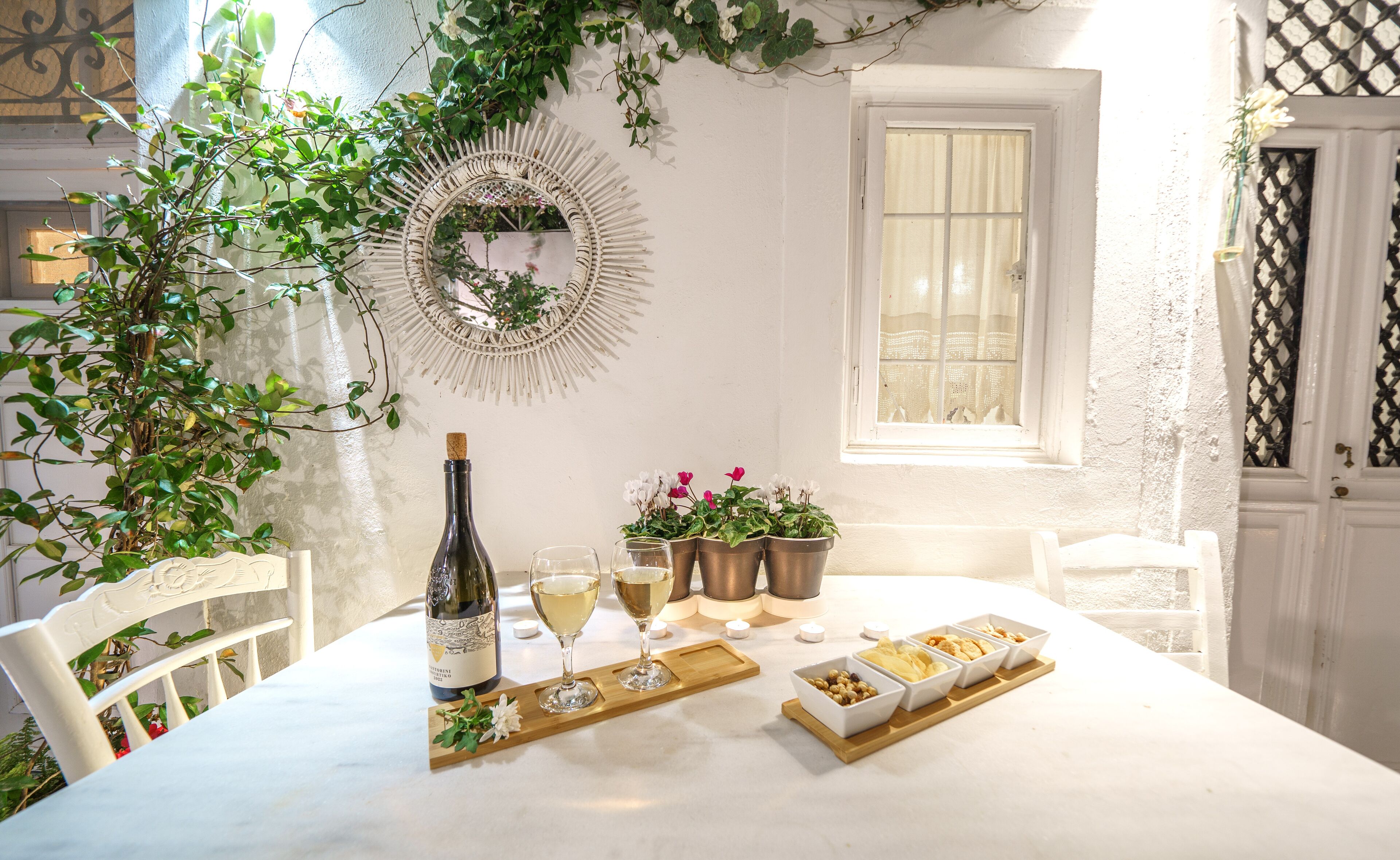 A table set with a bottle of wine, glasses, and a tray with food items.