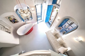 Ein modernes Interieur mit einer weißen Badewanne, einer Couch mit Kissen, einer blauen Tür und einer Deckenleuchte.