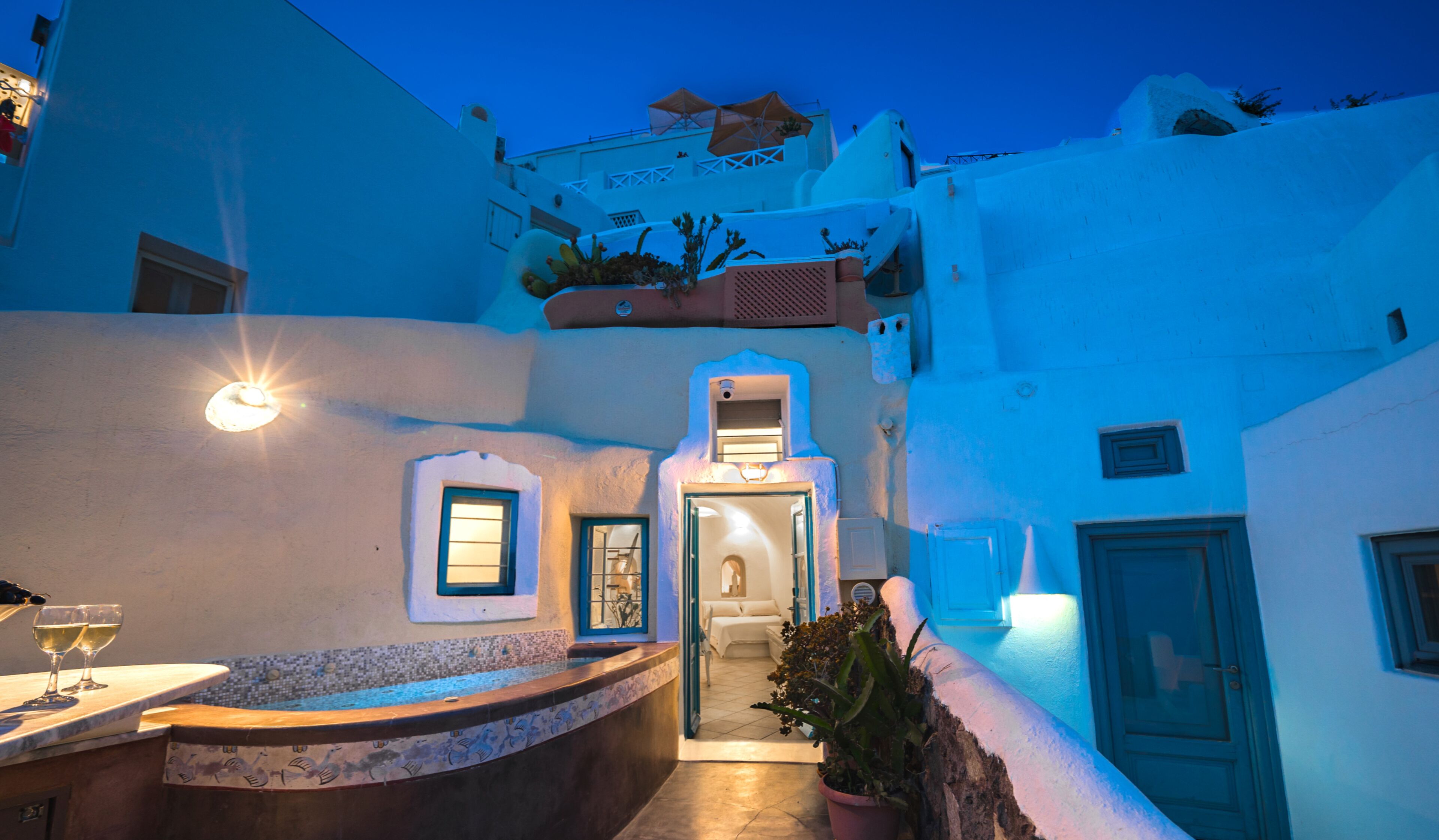 A narrow, white-walled courtyard with a small pool and a bar area.