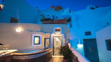 A narrow, white-walled courtyard with a small pool and a bar area.