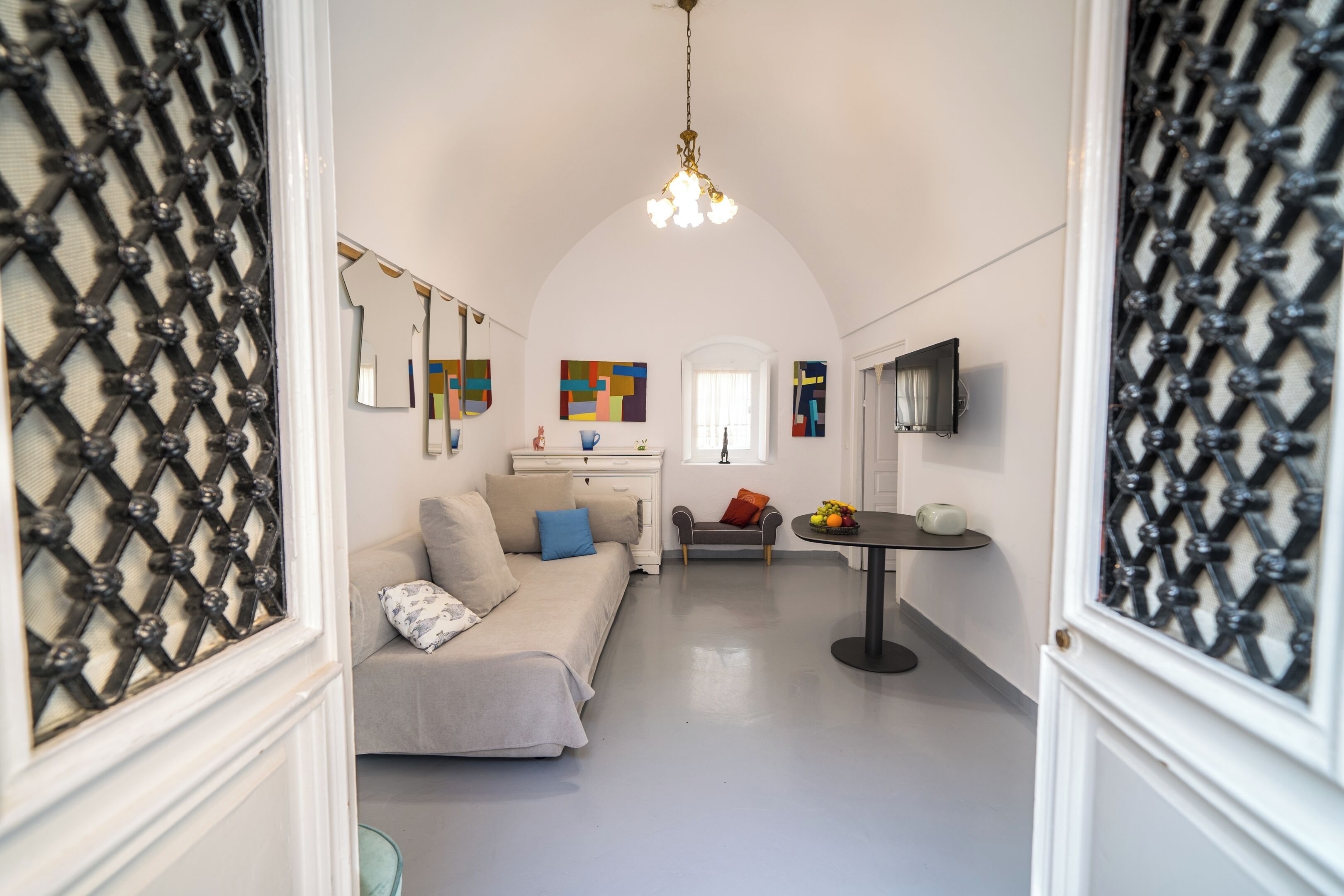A modern interior with a sofa, a small table with fruit, and abstract wall art.