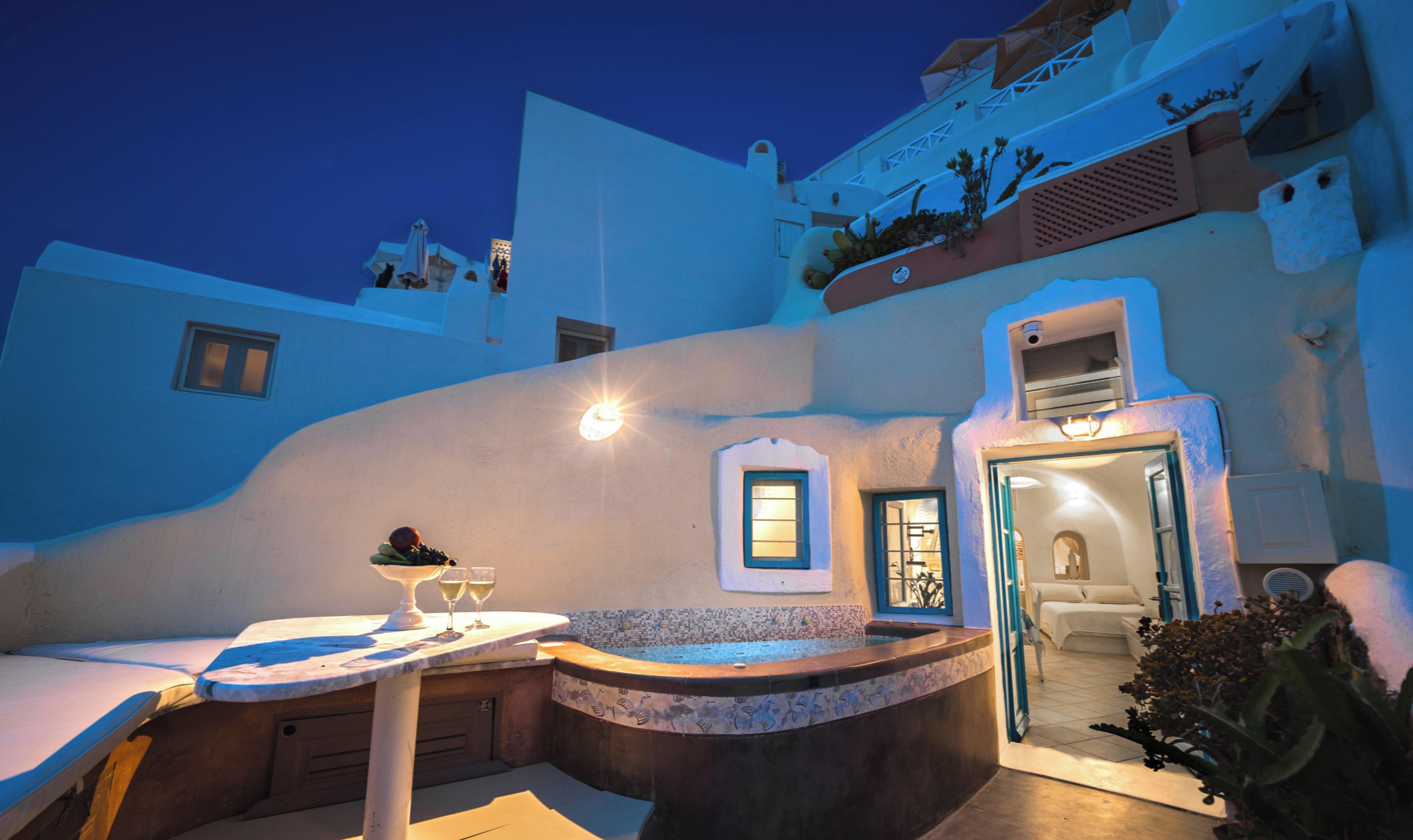 A sunken outdoor seating area with a table and chairs, a small window, and a door leading to an interior space.