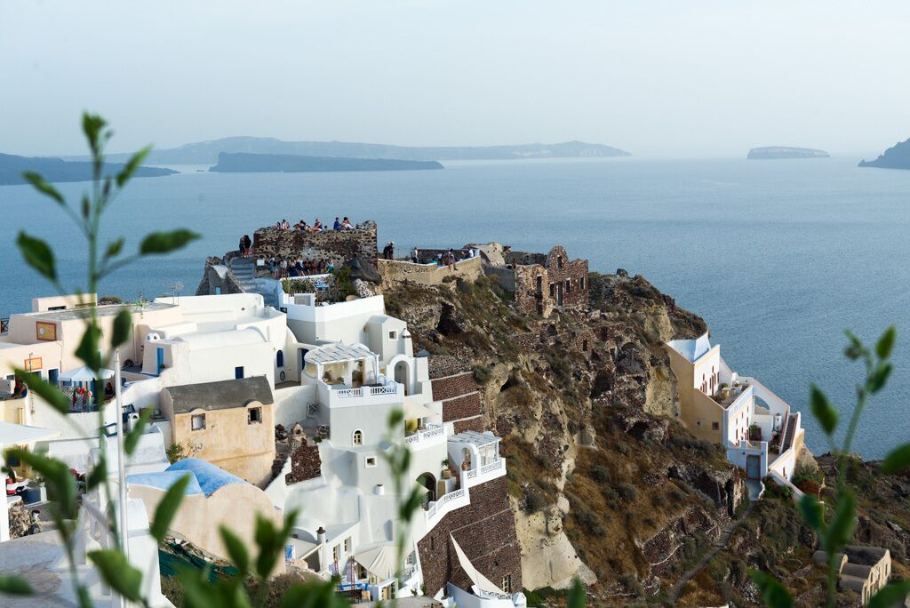 Un pueblo costero con edificios blancos, un acantilado rocoso y el mar al fondo.