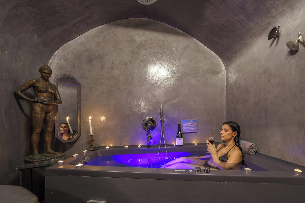 A spa room with a bathtub, a statue, and a mirror.