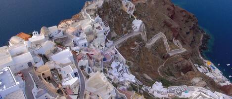 A coastal town with white buildings, narrow streets, and a rocky cliff overlooking the sea.