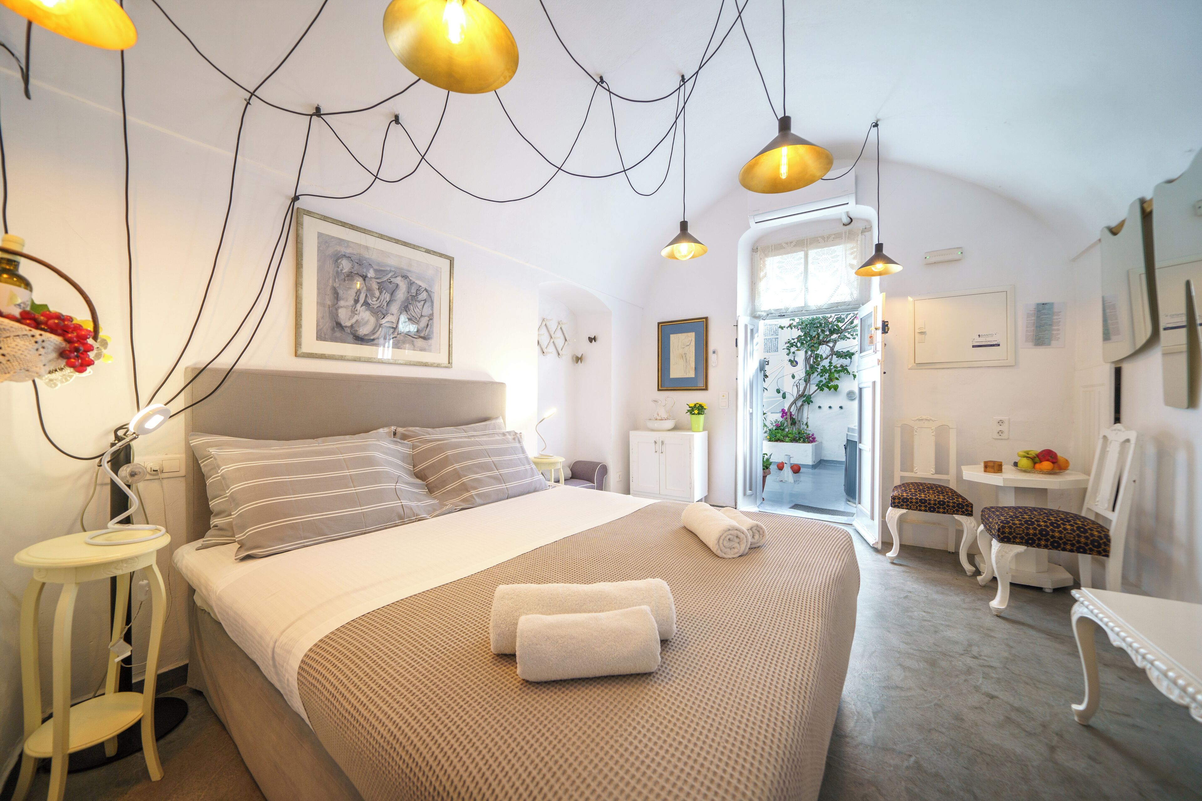 Un dormitorio con cama, mesita de noche, lámpara y vistas al exterior.