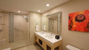 A modern bathroom with a glass shower enclosure, a double sink vanity, and a large mirror.