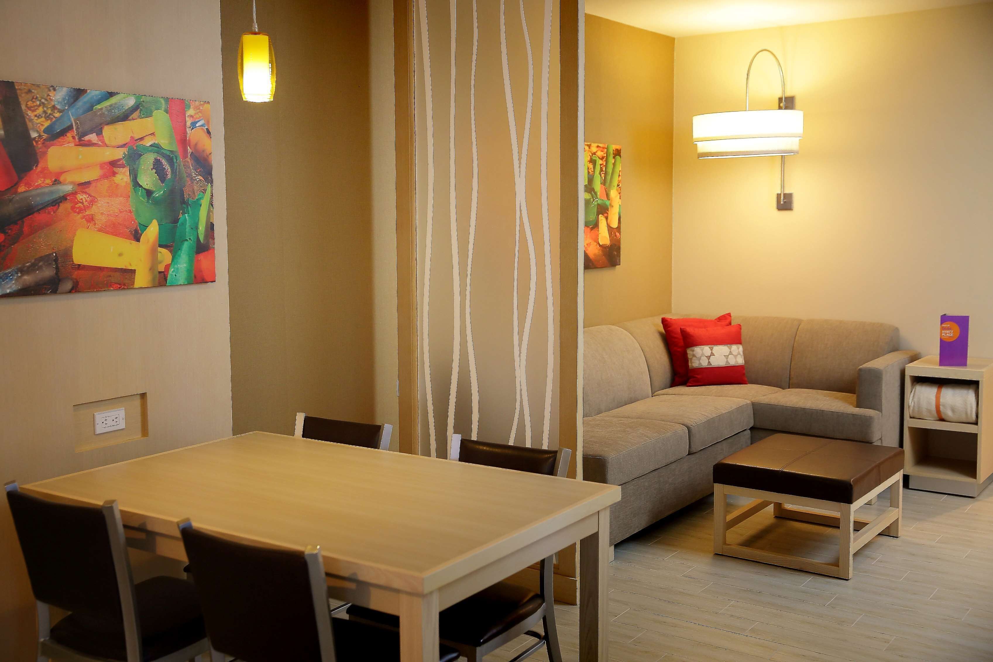 A living room with a sofa, a dining table with chairs, and two paintings on the walls.